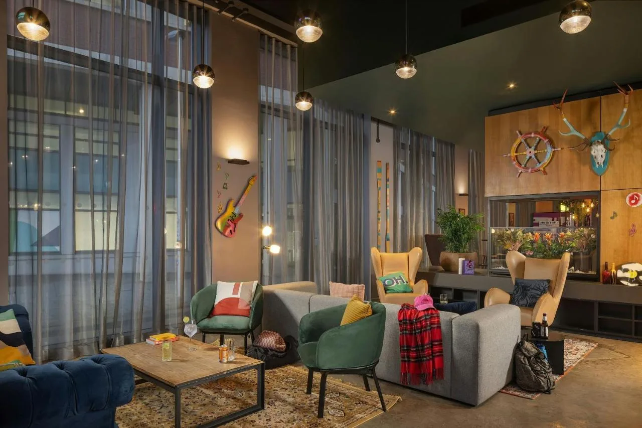 a living room with couches and chairs and a table at Moxy Glasgow Merchant City in Glasgow