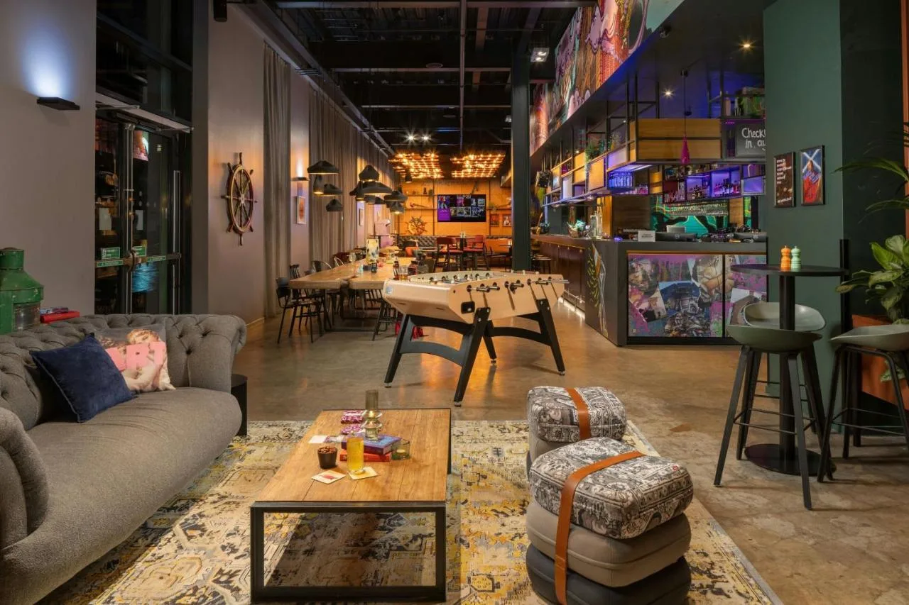 a living room with couches and a table and chairs at Moxy Glasgow Merchant City in Glasgow